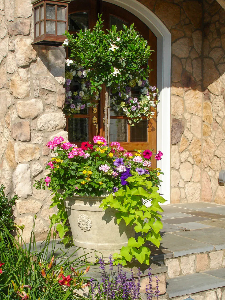 Tall stone entry planter with layered annual flowers